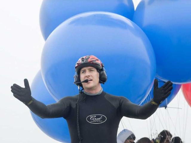 Matt Silver-Vallance asks people to clear the area prior to flew across the sea from Nelson Mandela's apartheid island prison using helium-filled giant party balloons in Cape Town. AFP