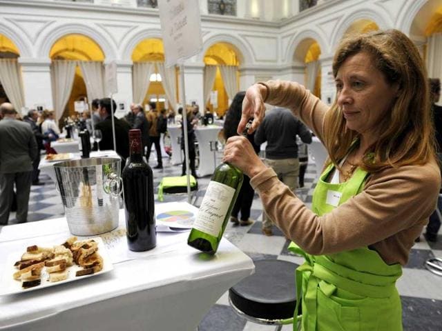 The owner of a wineyard in the Graves region of Bordeaux prepares a bottle of the 2012 production for tasting by professionals in the wine sector in the hall of the Bordeaux stock exchange during the opening of the week of primeur in the southwestern French region. AFP