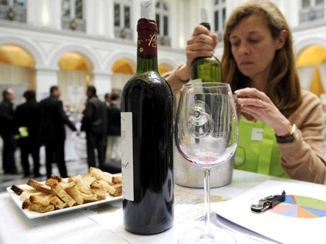 The owner of a wineyard in the Graves region of Bordeaux prepares a bottle of the 2012 production for tasting by professionals in the wine sector in the hall of the Bordeaux stock exchange during the opening of the week of primeur in the southwestern French region. AFP