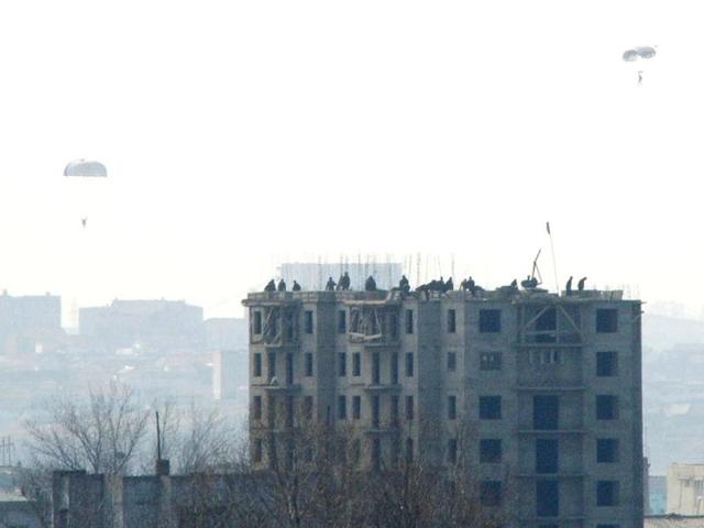 This photo taken from the Chinese border city of Dandong shows North Koreans parachuting down from their helicopter in Sinuiju, North Korea. AP Photo