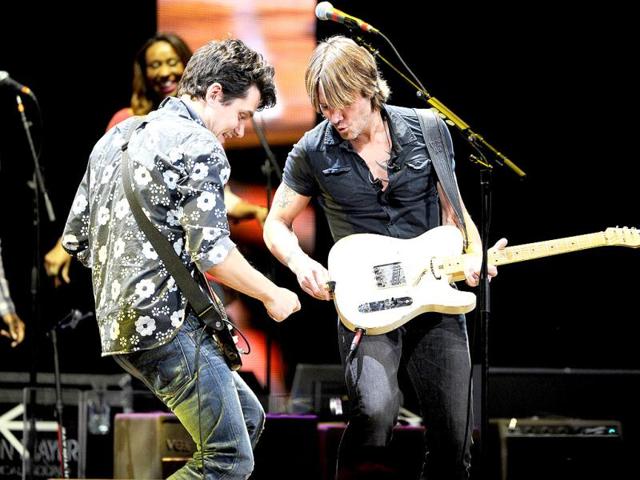 Musician John Mayer, left, helps Keith Urban when his guitar strap malfunctions during their performance together at Eric Clapton's Crossroads Guitar Festival 2013 at Madison Square Garden in New York. AP Photo