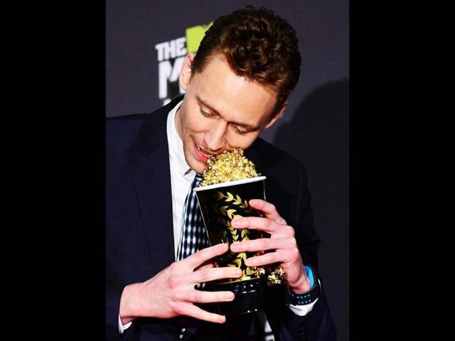 Tom Hiddlestone perhaps trying to eat the popcorn from his trophy as he poses in the press room during the 2013 MTV Movie Awards in Los Angeles, California, on April 14, 2013. (AFP Photo)