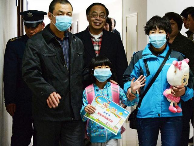 A seven-year-old girl who had Beijing's first human case of H7N9 bird flu with her parents as she prepares to go home from Ditan hospital in Beijing. (AFP)