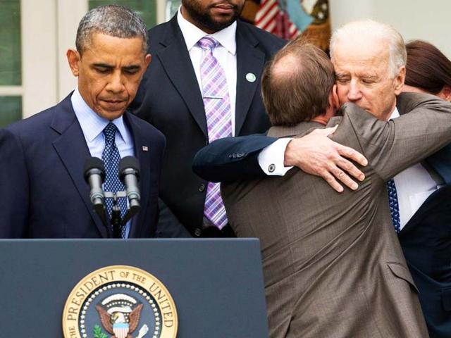 President Barack Obama stands at the podium at left as Mark Barden, the father of Newtown shooting victim Daniel is embraced by vice president Joe Biden during a news conference about measures to reduce gun violence in the Rose Garden of the White House, in Washington. (AP)