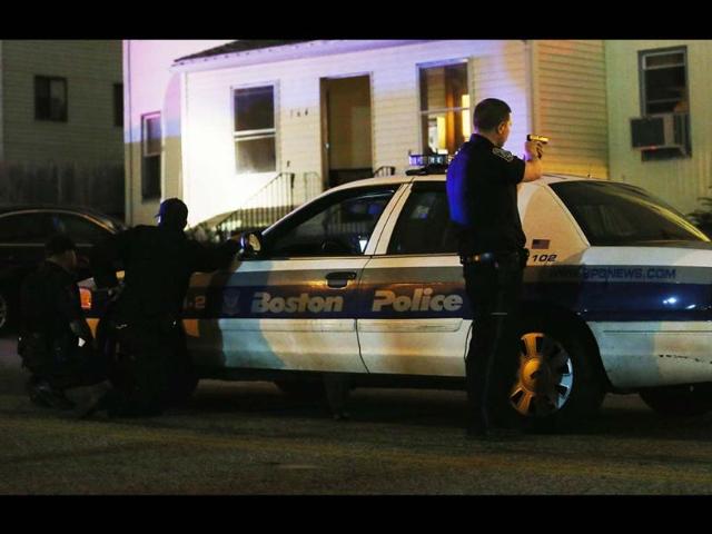 A police officer with gun drawn searches for a suspect in Watertown, Massachusetts. Earlier, a Massachusetts Institute of Technology campus police officer was shot and killed at the school's campus in Cambridge. A short time later, police reported exchanging gunfire with alleged carjackers in Watertown, who turned out to be the suspects accused of carrying out the Boston Marathon explosions. (AFP)