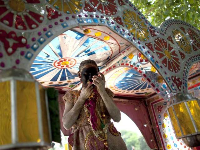 A youth puts on makeup as he stands underneath a decorated carriage whilst dressing as Hindu god Lord Hanuman before taking part in a procession for Ram Navami, which marks the birthday of Hindu god Lord Rama, in New Delhi. AFP