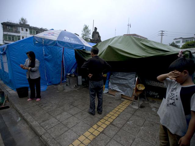 Residents displaced by Saturday's earthquake stand outside tents set up in Lushan county in southwestern China's Sichuan province. AP