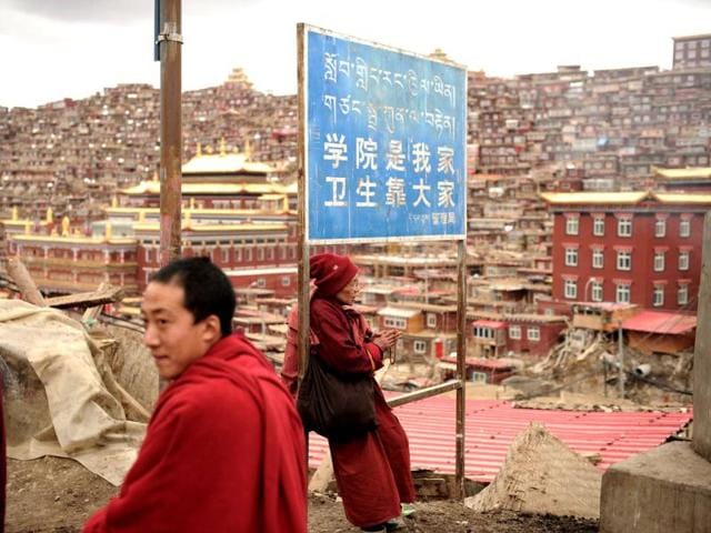A Buddhist nun sitting, reading under a sign that reads "the campus is our home, maintaining hygiene is everyone's responisbility", in Seda Monastery, the largest Tibetan Buddhist school in the world, with up to 40,000 monks and nuns in residence for some parts of the year. (AFP)
