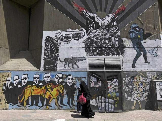 A woman walks with her daughter past graffiti denouncing the interior ministry and members of Muslim Brotherhood in Cairo. (Reuters)