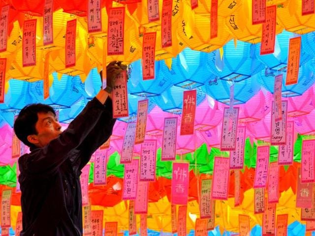A South Korean worker attaches a name card with a wish by Buddhist followers to a lotus lantern at Chogye Temple ahead of Buddha's birthday in central Seoul. AFP