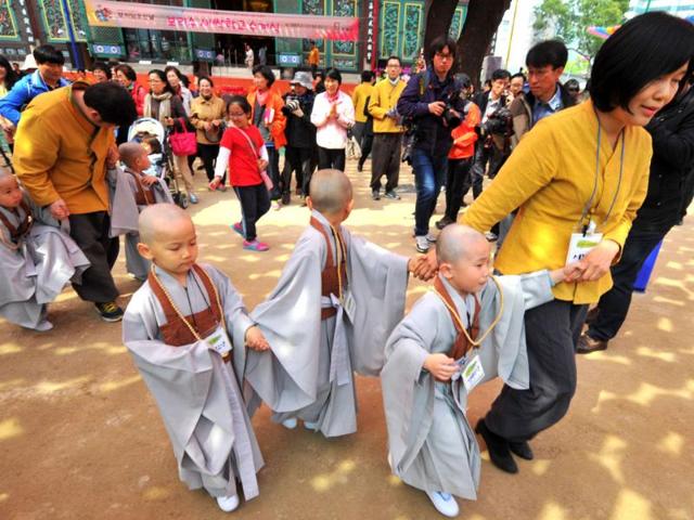 Young South Korean Buddhists with freshly shaved heads walk with their families after attending a ceremony called "children becoming Buddhist monks" at Chogye Temple ahead of Buddha's birthday in central Seoul. AFP