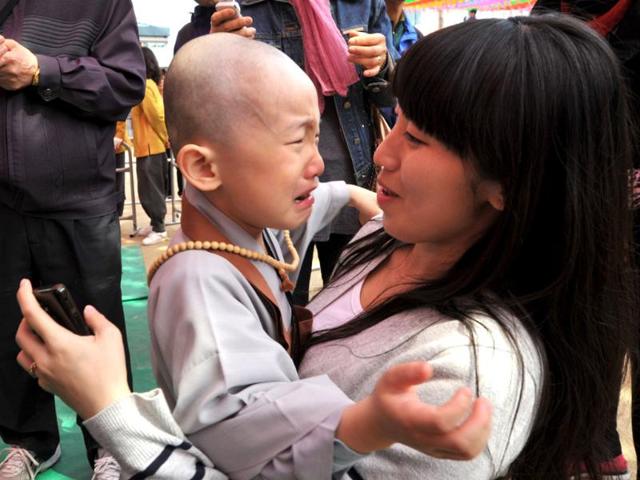 A buddhist child is held by his mother after having his head shaved at Chogye Temple in central Seoul. AFP