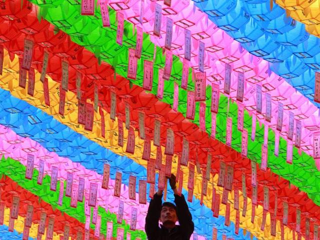 A worker attaches the name tag of a Buddhist who made a donation to a lantern ahead of upcoming Buddha's birthday at the Jogye temple in Seoul, South Korea. AP