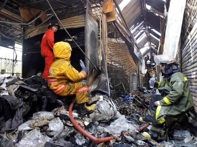 Firefighters rest at shops, destroyed after a fire broke out, at Chatuchak Market in Bangkok. Reuters photo