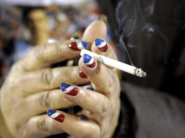 A Uruguay's Nacional fan with her nails painted with the colors of the team smokes a cigarette before a Copa Libertadores soccer match in Montevideo. AP photo
