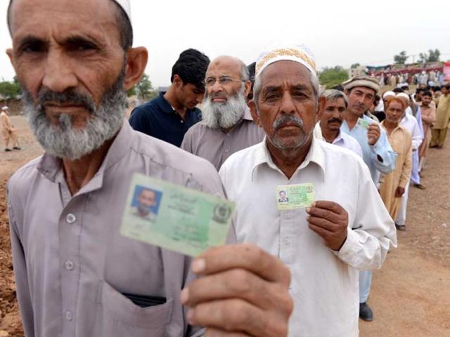 Voters display their national identity cards as they stand in a queue waiting for their turn to cast their vote outside a polling station in Islamabad. AFP photo