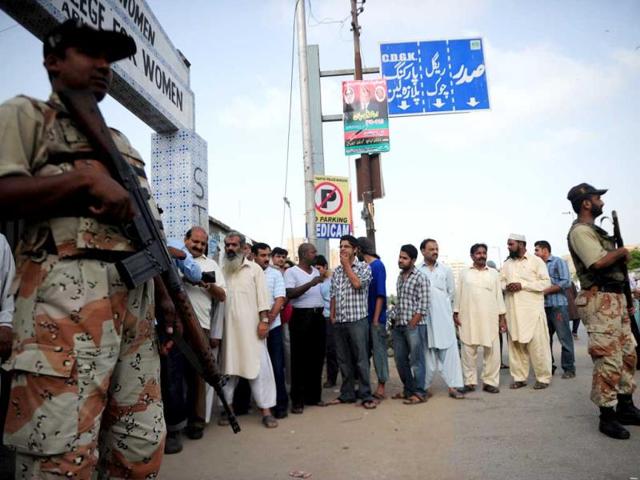 Paramilitary soldiers stand guard as voter squeue for their turn to cast their vote outside a polling station in Karachi. AFP photo