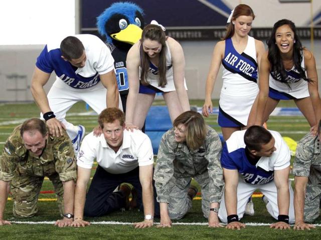 Britain's Prince Harry kneels down at the bottom of a pyramid of cheerleaders, US and British military officials and near the US Air Force Academy mascot "The Bird" at the academy in Colorado Springs, Colorado. (AP)