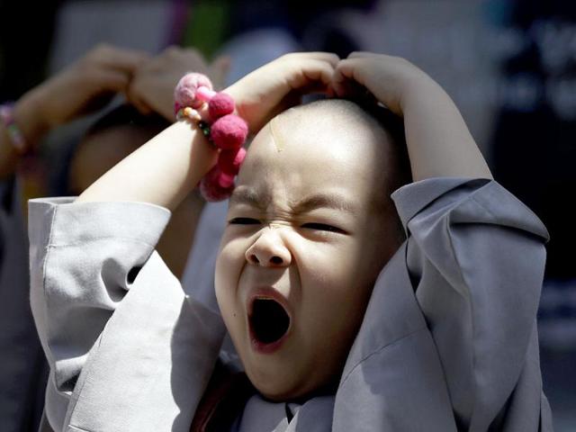 A shaven-headed young boy yawns while attending a volunteer activity in Seoul, South Korea. He is among ten children who entered a temple to have an experience of monks' life for three weeks, called Little Buddha Camp, to celebrate upcoming Buddha's birthday on May 17. AP Photo