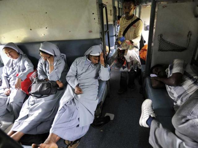 Nuns take a nap inside the sleeper class compartment of Vivek Express, the longest rail route of India on Sunday as a roving salesman comes with Chinese goods, May 05 2013. (Photo by Arijit Sen / Hindustan Times)
