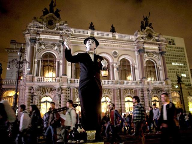 An artist dressed as Charlie Chaplin performs in front of Municipal Theater as part of the annual art event Virada Cultural in Sao Paulo, Brazil. (AP Photo)