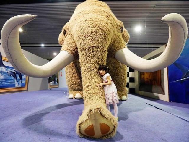 A girl cuddles a full-scale replica of a mammoth on display as part of International Children's Day celebration at a museum in Wuha, Hubei province. (Reuters)