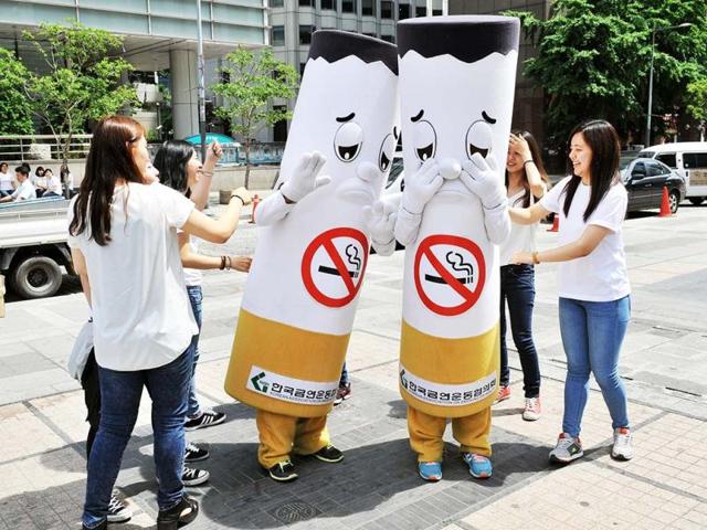 South Korean activists hit cigarette-shaped outfits during a campaign marking the World No Tobacco Day in Seoul. (AFP)