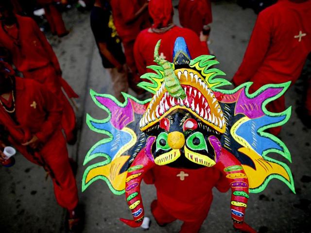 A participant of the "Diablos Danzantes" (Dancing Devils) of Yare dons a mask to mark the Feast of Corpus Christi in San Francisco de Yare. The dancers perform the ritual dance celebrating the transformation of the body and blood of Christ into bread and wine. (Reuters)