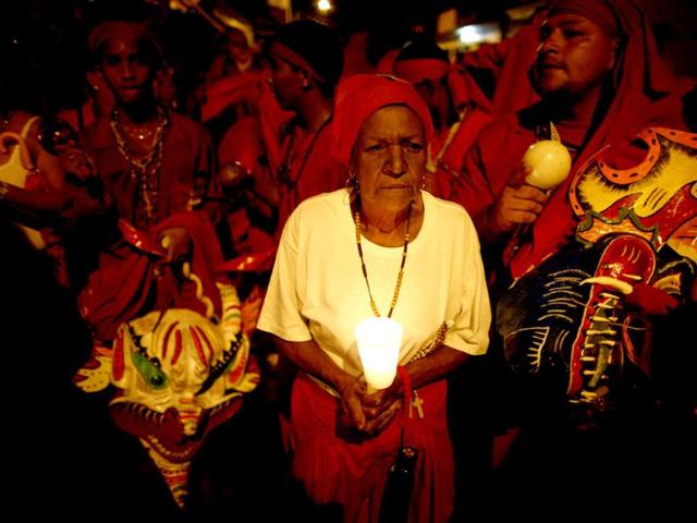 A woman holds a candle as she stands among "Diablos Danzantes" (Dancing Devils) of Yare during the Feast of Corpus Christi in San Francisco de Yare. The annual festival celebrates the transformation of the body and blood of Christ into bread and wine. (Reuters)