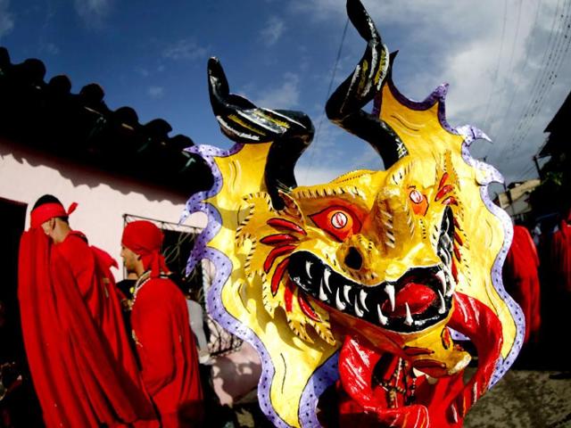 A participant of the "Diablos Danzantes" (Dancing Devils) of Yare wears a mask as they perform to mark the Feast of Corpus Christi in San Francisco de Yare. The dancers perform the ritual dance celebrating the transformation of the body and blood of Christ into bread and wine. (Reuters)