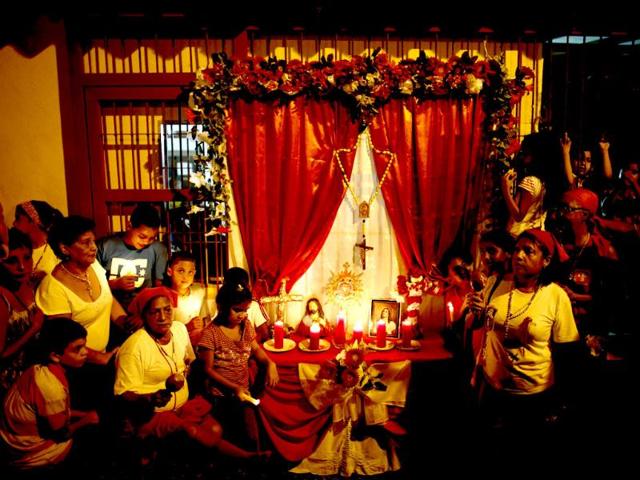 A family surrounds an altar outside their home to wait for the "Diablos Danzantes" (Dancing Devils) of Yare during the Feast of Corpus Christi in San Francisco de Yare. The annual festival celebrates the transformation of the body and blood of Christ into bread and wine. (Reuters)