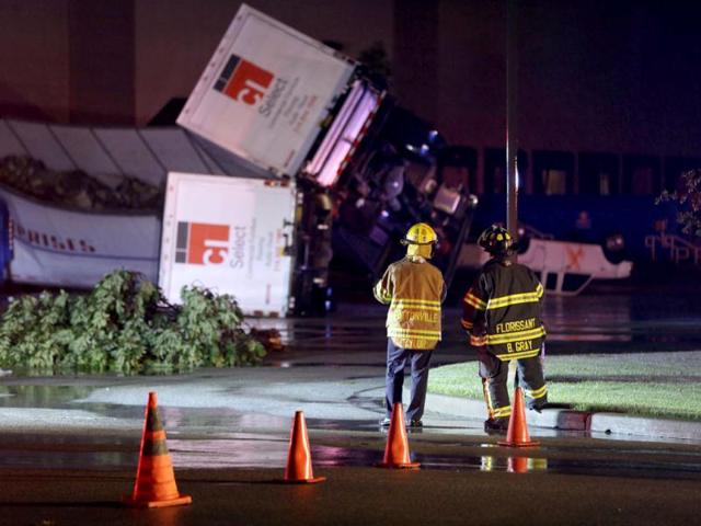Rescue personnel stand near overturned trucks in an industrial park after strong storms moved through the area in St. Louis. (AP)