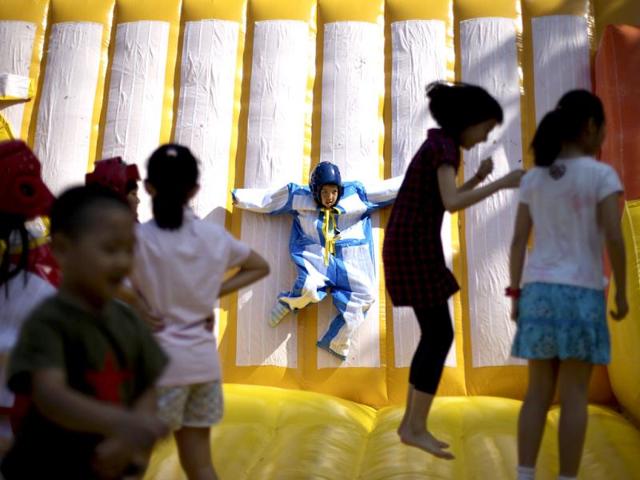 A child plays on a sticky wall as others jump on an inflatable balloon bouncer on International Children's Day organized by the Chinese Foreign Affairs Office at Children's Palace of Dongcheng district in Beijing. (AP)