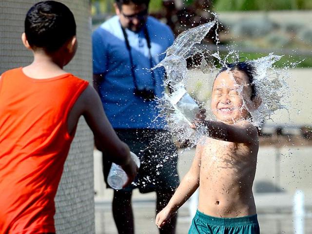 Children cool off in a water fountain plaza at Grand Park in downtown Los Angeles, California where summer afternoon temperatures reached 75 degrees Fahrenheit. AFP