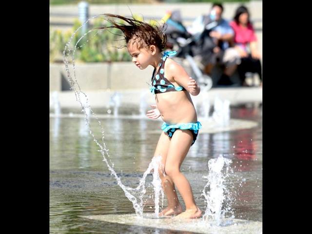 A child cools off in a water fountain plaza at Grand Park in downtown Los Angeles, California where summer afternoon temperatures reached 75 degrees Fahrenheit. AFP