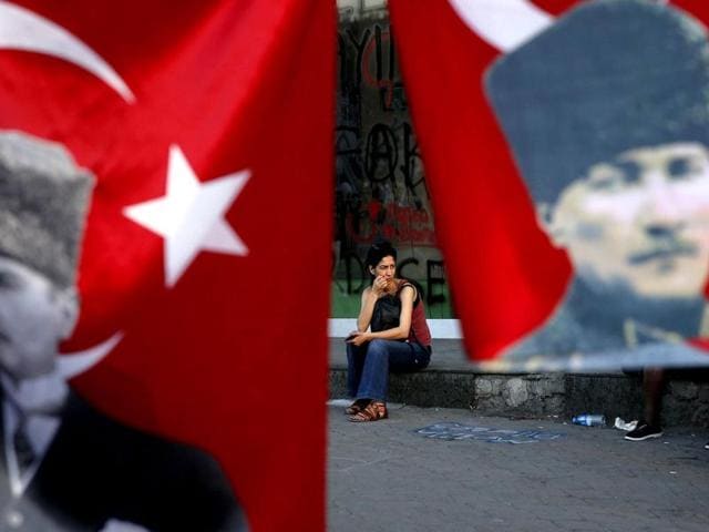 A woman is framed by Turkish flags depicting the founder of modern Turkey, Mustafa Kemal Ataturk, in Istanbul's Taksim square. Reuters