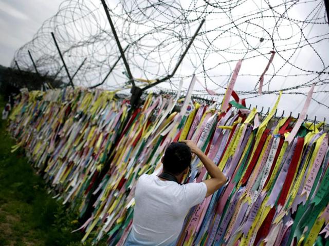 A man takes souvenir photos in front of a wire fence decorated with ribbons carrying messages visitors left wishing for the reunification of the two Koreas, at the Imjingak Pavilion near the border village of Panmunjom, which has separated the two Koreas since the Korean War, in Paju, north of Seoul, South Korea. AP Photo