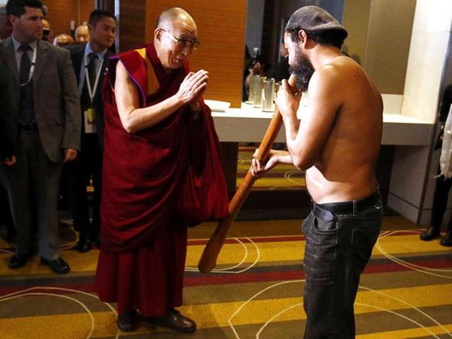 An Australian Aboriginal man plays a wooden wind instrument known as a didgeridoo as the Tibetan spiritual leader the Dalai Lama arrives at a media conference in Sydney. (Reuters)