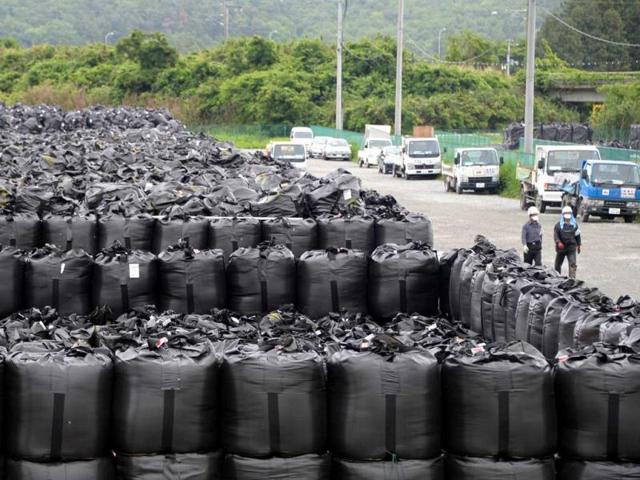 Workers walk beside bags of contaminated earth at a collection site after a decontamination operation at Naraha town in Fukushima prefecture. Naraha town was inside the 20 km exclusion zone of the troubled Fukushima Dai-ichi Nuclear Power Plant following the 2011 quake and tsunami and the town is preparing for local residents to return. (AFP)