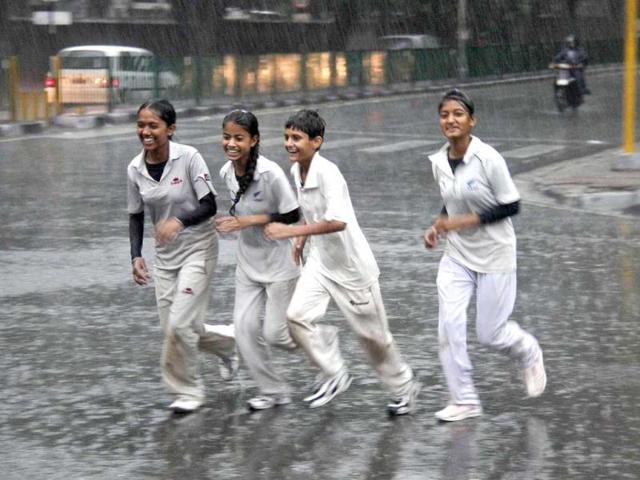 Children run along a road during a heavy rain shower in Chandigarh. Reuters photo