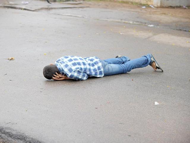 A Telangana Joint Action Committee (T-JAC) activist lies on the road after being hit by a tear gas shell fired by police during a pro-Telangana protest in Hyderabad on June 14, 2013. AFP/Noah Seelam