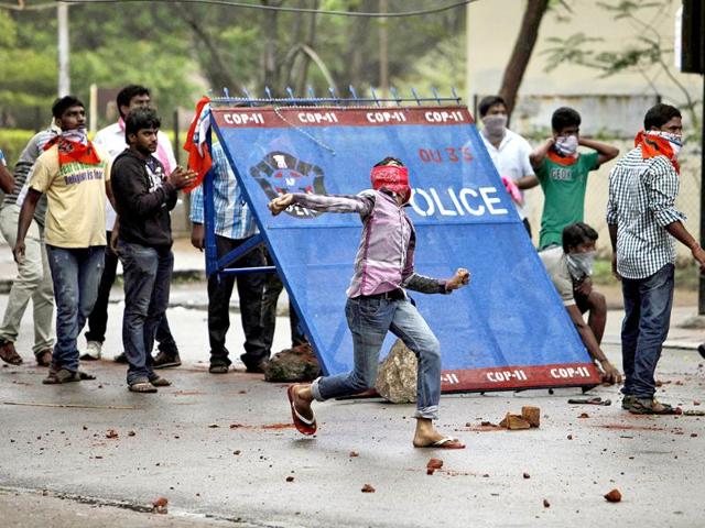 Student protestor hurls stones at policemen during a protest demanding creation of a new state 'Telangana' in Hyderabad on June 14, 2013. AP/Mahesh Kumar A