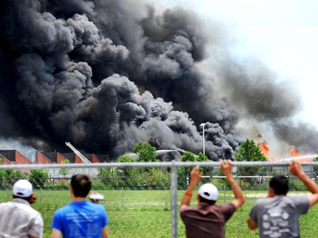 Spectators watch a fire engulf a sprawling mixed-use building near downtown Indianapolis filled with tires and wooden pallets producing a towering pillar of black smoke that prompted the evacuation of a five-block area surrounding the structure. AP