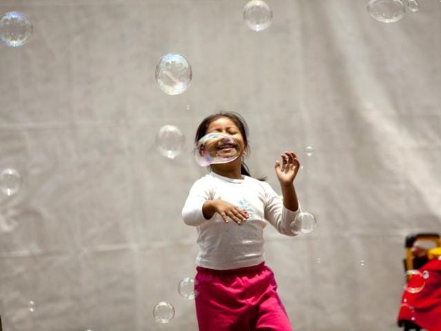 A girl swats at airborne bubbles at the inauguration of the Tlalpan Taco Fair featuring 20 different tacos, in Mexico City. AP
