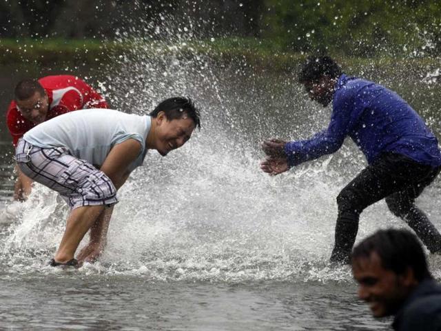 People having fun in a water puddle near Rajghat lawn during a spell pre-monsoon rain in New Delhi. HT/Raj K Raj