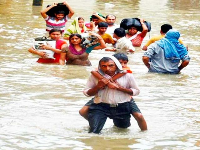 People wade through a flooded street after heavy rains lashed Saharanpur. PTI Photo