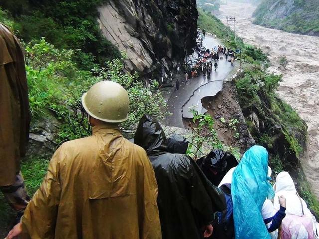 People look at a collapsed road and the flooded river in Uttarakhand. AFP