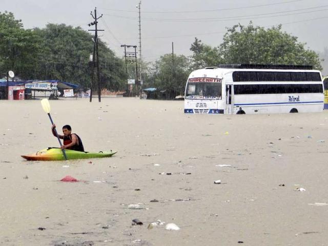 A man rows past a bus partly submerged in flood water in Rishikesh, Uttarakhand. (AP Photo)