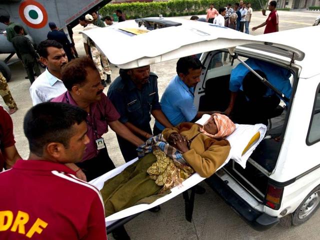 Disaster relief personnel assist an elderly woman into an ambulance after being evacuated from flood-hit areas at the Jolly Grant Airport in Dehradun. (AFP/Ministry of Defence/Gurudutt Mehra)