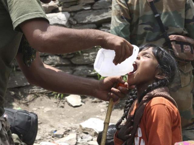 Army soldier helps a young girl, affected by floods, drink water before evacuating her from the upper reaches of mountains, in Gaurikund. (AP)